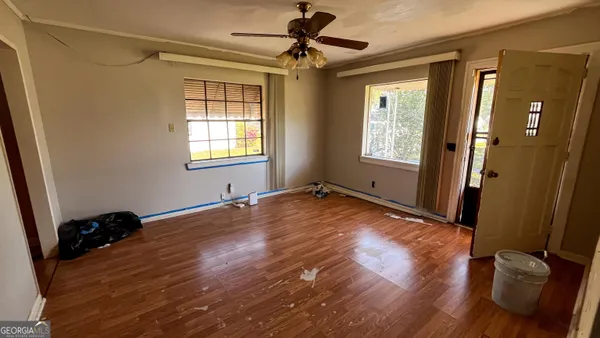 a view of empty room with wooden floor and fan
