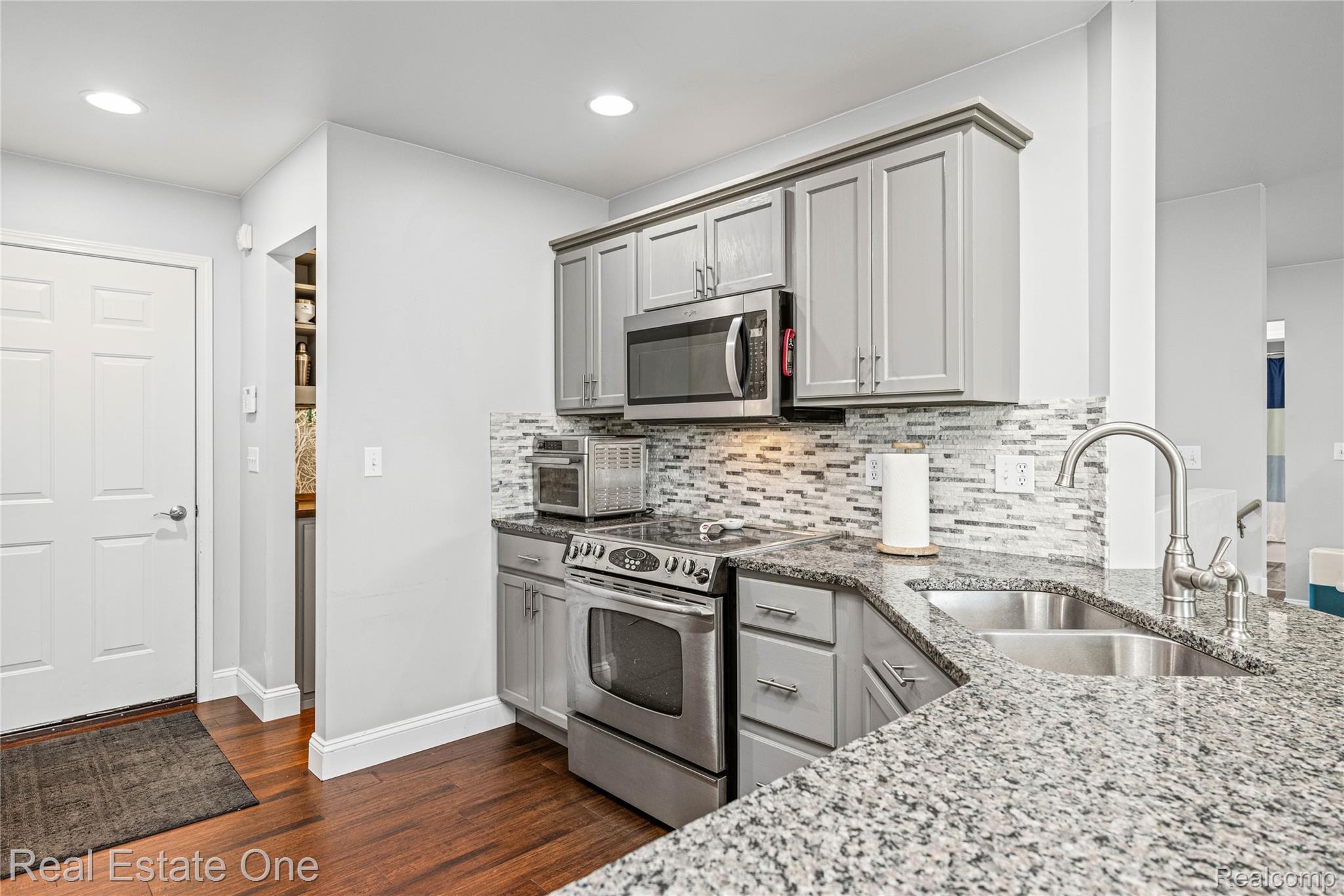 2479 Gibson Road Grand Blanc, MI 48439 - Photo 22 of 55 Kitchen featuring light gray cabinetry, stainless steel appliances, a mosaic tile backsplash, and granite countertops