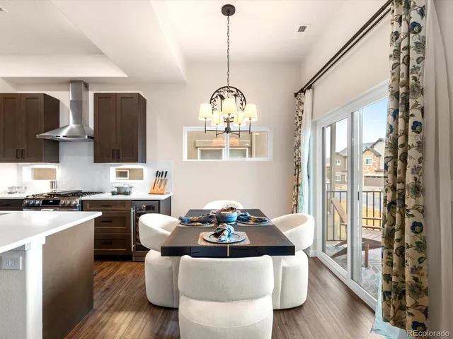 a kitchen with stainless steel appliances granite countertop a stove a sink dishwasher a dining table and chairs with wooden floor