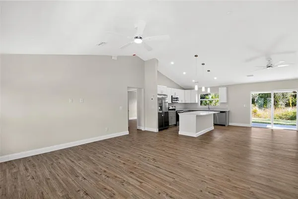 a view of kitchen with kitchen island microwave and stove with wooden floor