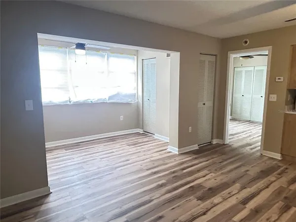 a view of an empty room with wooden floor and a window