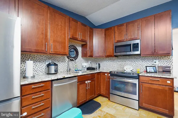 a kitchen with stainless steel appliances granite countertop wooden cabinets a stove top oven a sink and dishwasher
