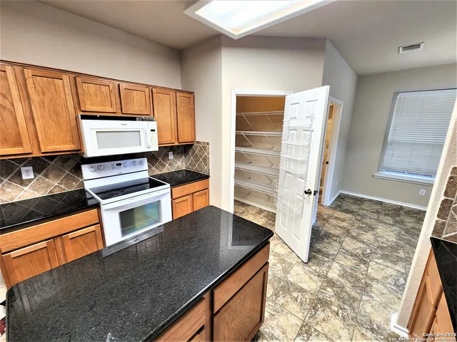 a kitchen with granite countertop a refrigerator and a stove top oven
