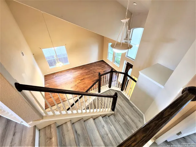 an empty room with wooden floor chandelier fan and windows