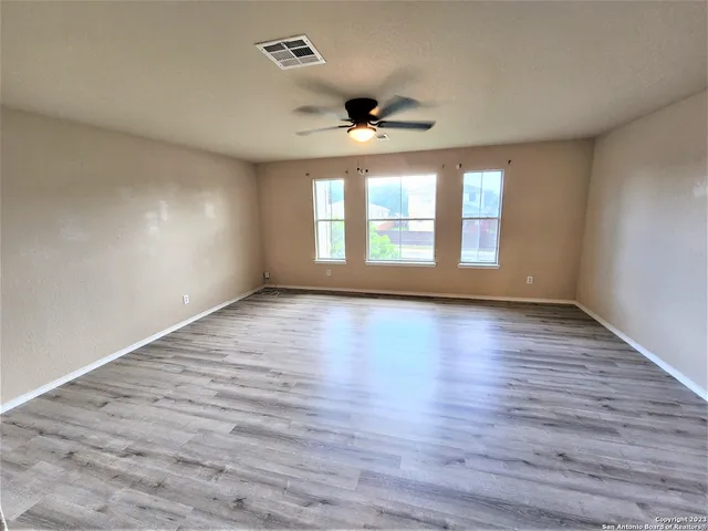 an empty room with wooden floor and windows