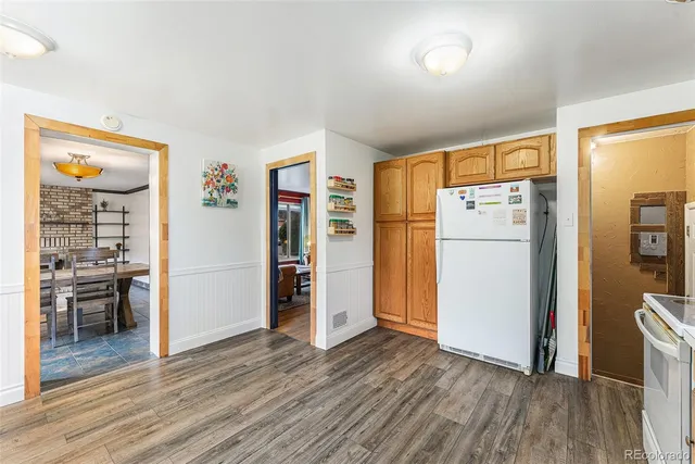 a view of a kitchen with refrigerator and wooden floor