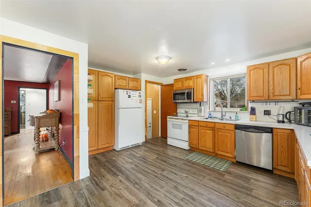 a kitchen with stainless steel appliances granite countertop a refrigerator a sink dishwasher a stove with wooden cabinets and floor