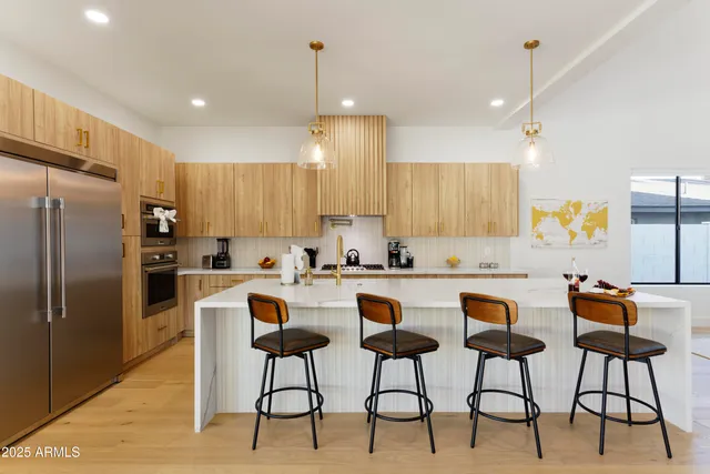 a kitchen with stainless steel appliances granite countertop a stove a sink a refrigerator a dining table and chairs