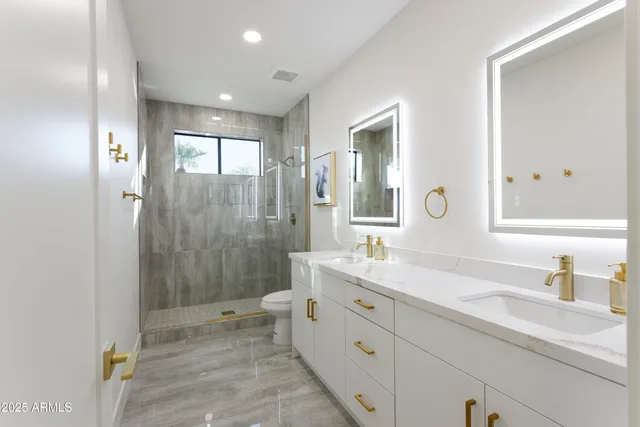 a spacious bathroom with double sink a large mirror and shower