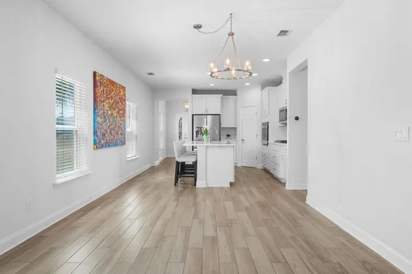 a view of a livingroom with wooden floor and a kitchen