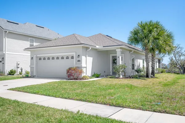 a view of a house with a yard and a large tree