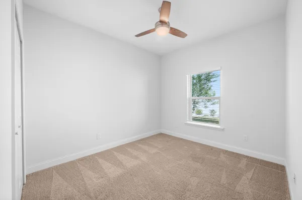 an empty room with a ceiling fan and carpet