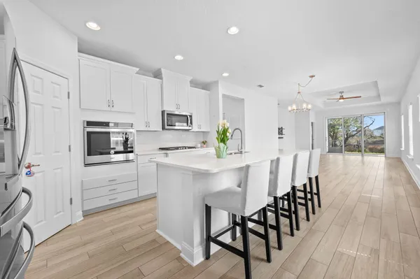 a kitchen with stainless steel appliances kitchen island granite countertop a wooden floor and white cabinets