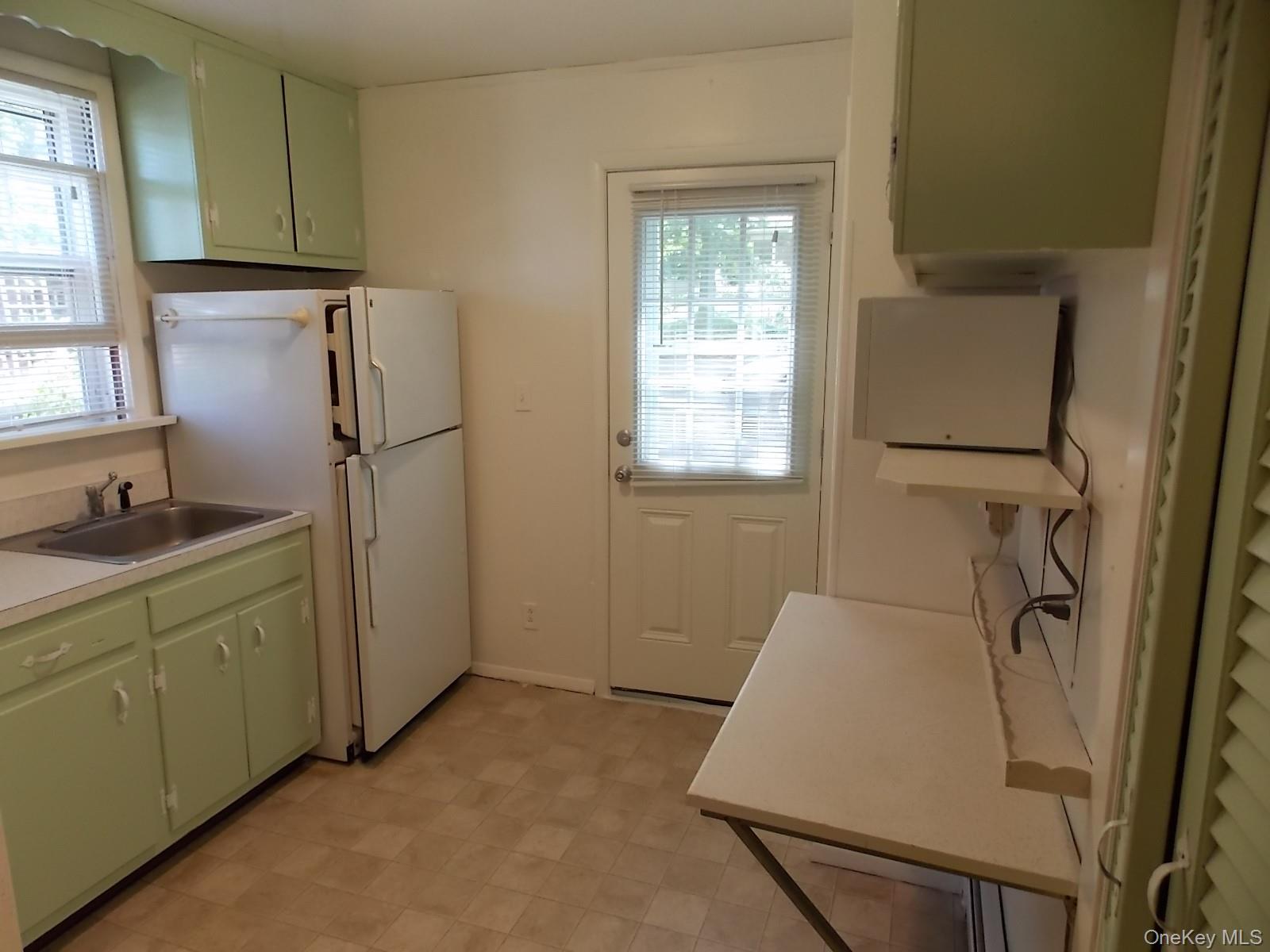 111 Lakeside Trail, Unit A Ridge, NY 11961 - Photo 3 of 7 a room with a refrigerator and window