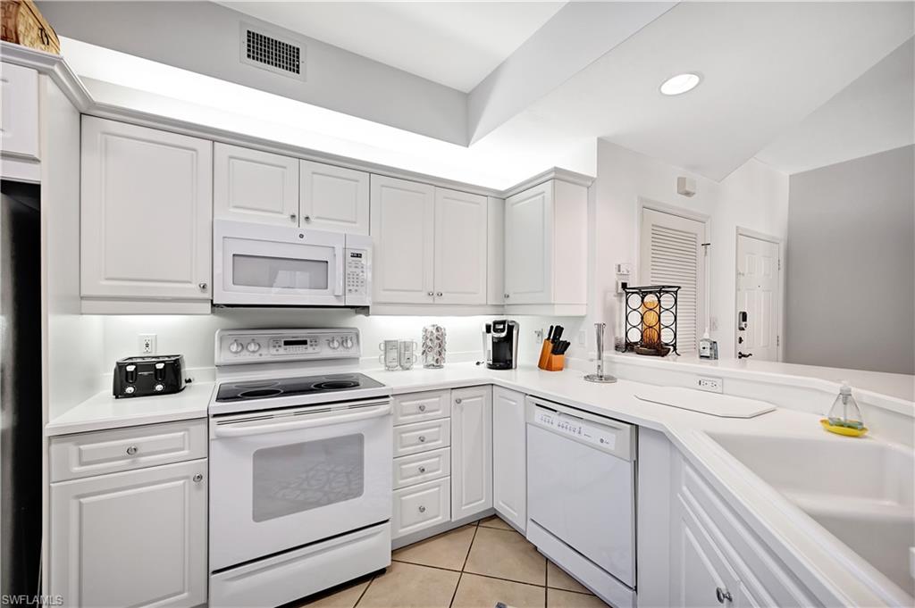 410 Bayfront Place, Unit 2409 Naples, FL 34102 - Photo 8 of 23 a kitchen with white cabinets white appliances sink and cabinets