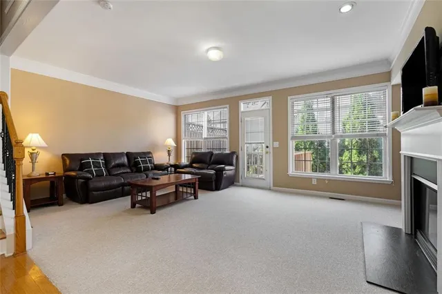 a living room with furniture floor to ceiling window hardwood floor and a flat screen tv