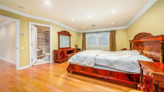a spacious bedroom with a bed and dresser with mirror