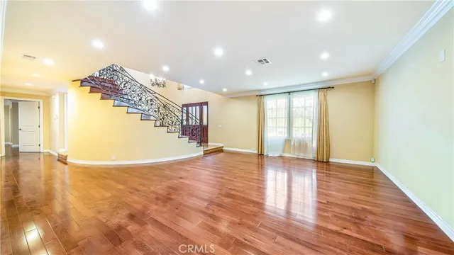 a view of an empty room with wooden floor and windows