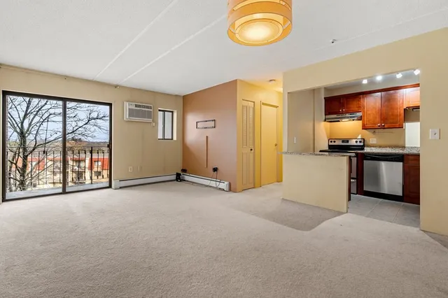 an empty room with a kitchen view and a large window