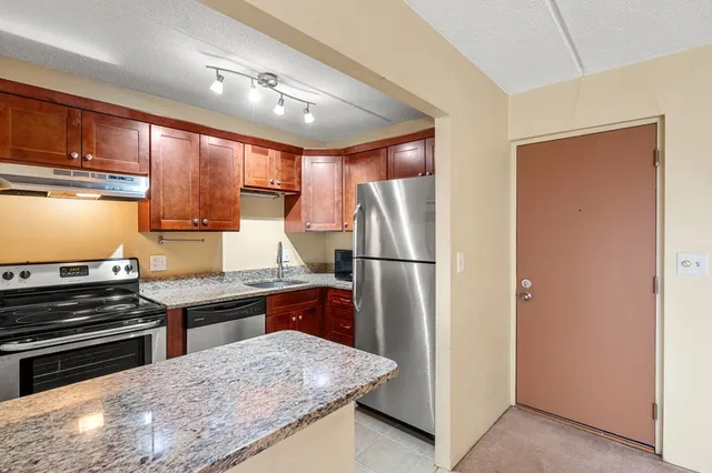 a kitchen with stainless steel appliances granite countertop a refrigerator and a stove top oven