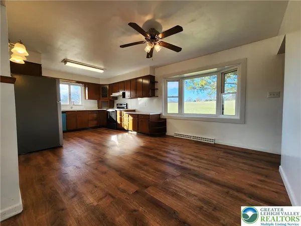 a view of an empty room with window and wooden floor