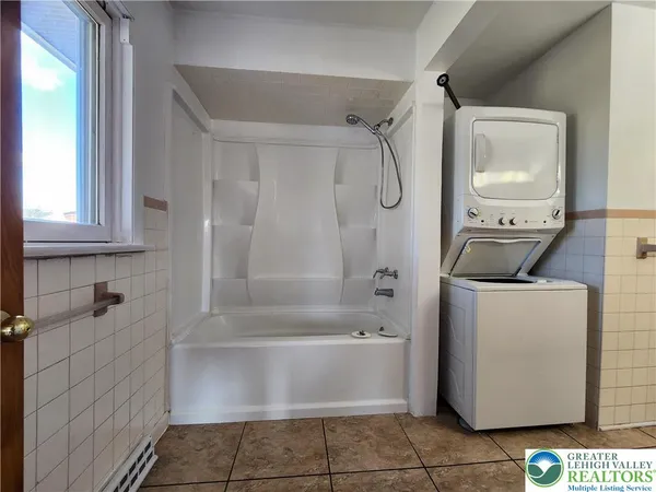 a bathroom with a tub a mirror and shower