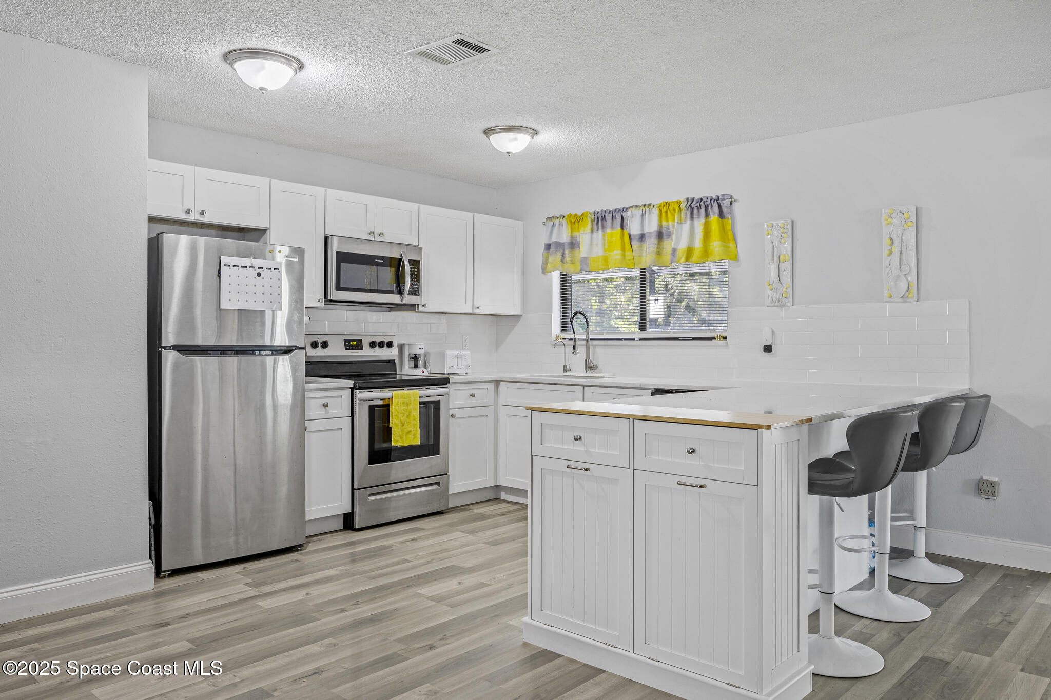 797 Tooley Road Southwest Palm Bay, FL 32908 - Photo 2 of 38 a kitchen with granite countertop a refrigerator cabinets and wooden floor