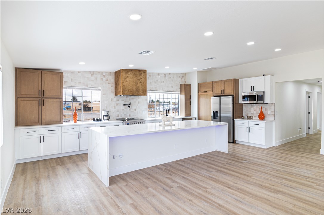 1891 Brian Road Pahrump, NV 89048 - Photo 6 of 50 Kitchen featuring visible vents, backsplash, a kitchen island, light wood-style floors, and stainless steel appliances
