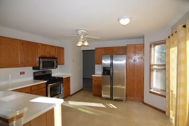 a kitchen with stainless steel appliances kitchen island granite countertop a refrigerator and a stove top oven