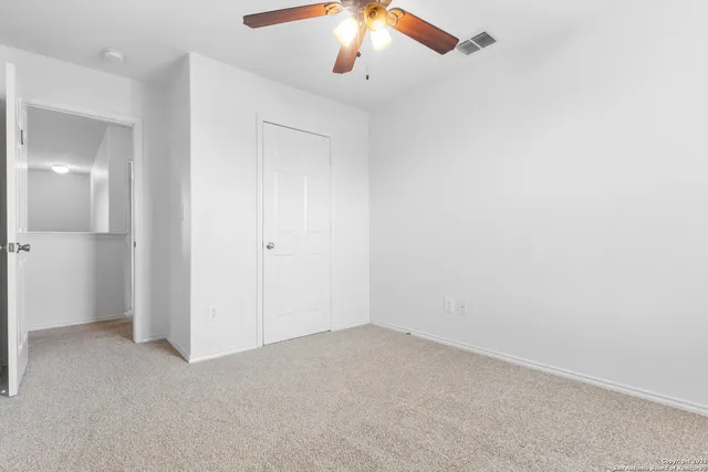 an empty room with a window and a ceiling fan