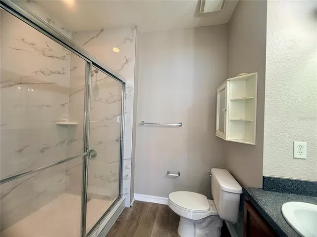 a bathroom with a granite countertop sink toilet and shower