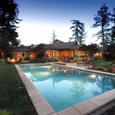 a view of swimming pool that has lawn chairs with plants and trees