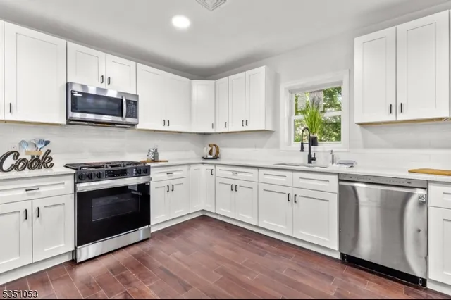 a kitchen with granite countertop white cabinets and white stainless steel appliances