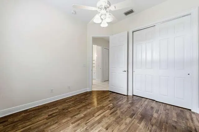 an empty room with wooden floor fan and windows