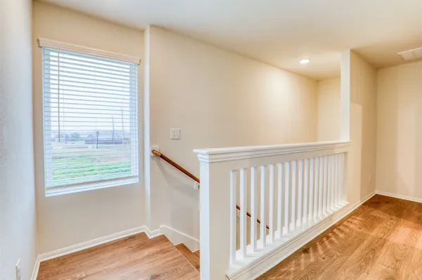 a view of a hallway with wooden floor and a bathroom
