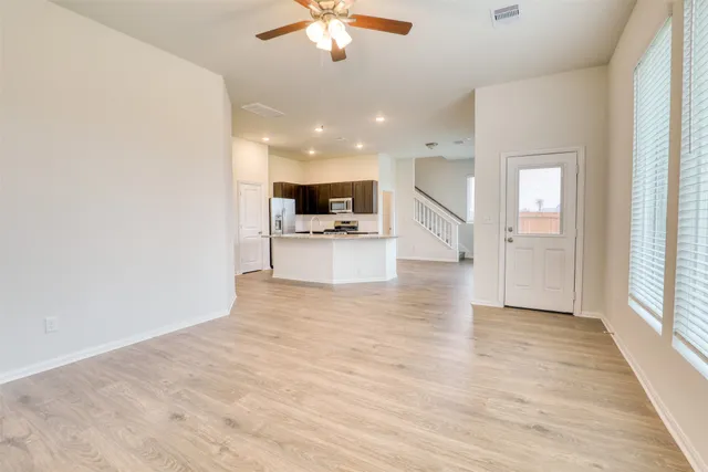 a view of an empty room with a window and a kitchen