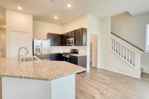 a kitchen with stainless steel appliances granite countertop a sink refrigerator and cabinets