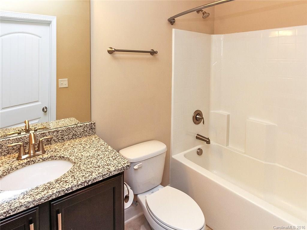 233 Annatto Way, Unit 553 Tega Cay, SC 29708 - Photo 15 of 22 a bathroom with a granite countertop sink toilet mirror and bathtub