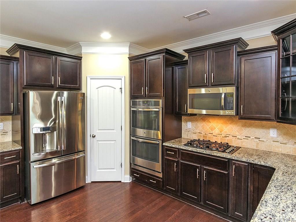 233 Annatto Way, Unit 553 Tega Cay, SC 29708 - Photo 3 of 22 a kitchen with granite countertop stainless steel appliances and wooden floor