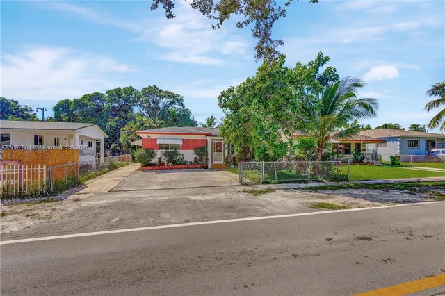 a front view of a house with a garden and trees