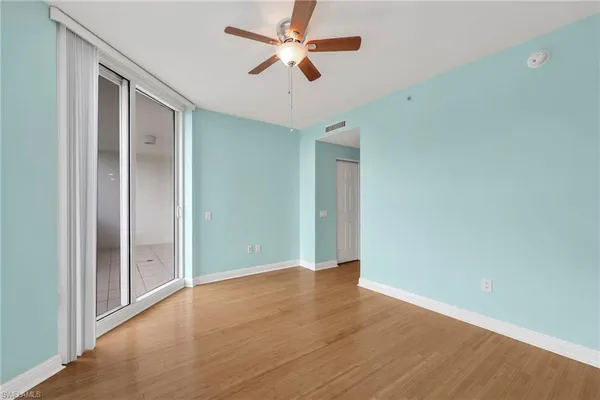 a view of an empty room with window and wooden floor