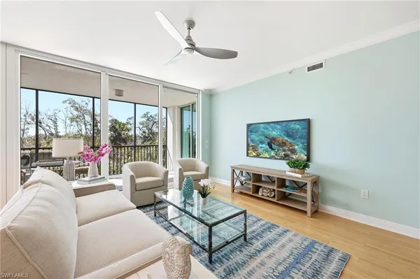 a living room with furniture a rug potted plant and a large window