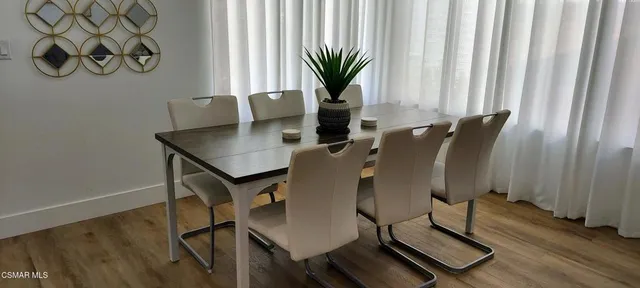 a kitchen with stainless steel appliances granite countertop a refrigerator a stove a sink a dining table and chairs