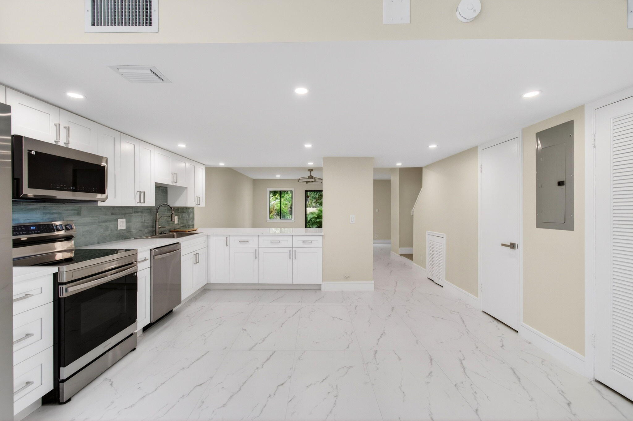 1330 Northwest 13th Street, Unit 12 Boca Raton, FL 33486 - Photo 5 of 52 a large white kitchen with stainless steel appliances granite countertop a stove a sink and a microwave