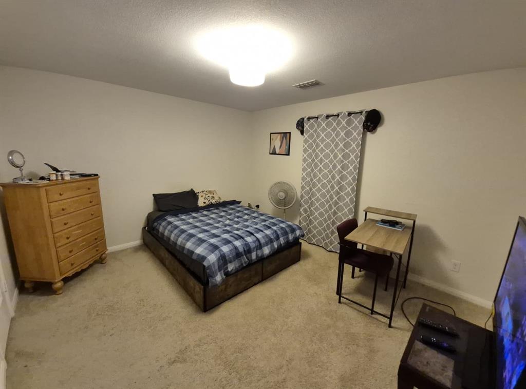 14249 Bridgeview Lane Dallas, TX 75253 - Photo 2 of 9 Bedroom with light colored carpet and a textured ceiling