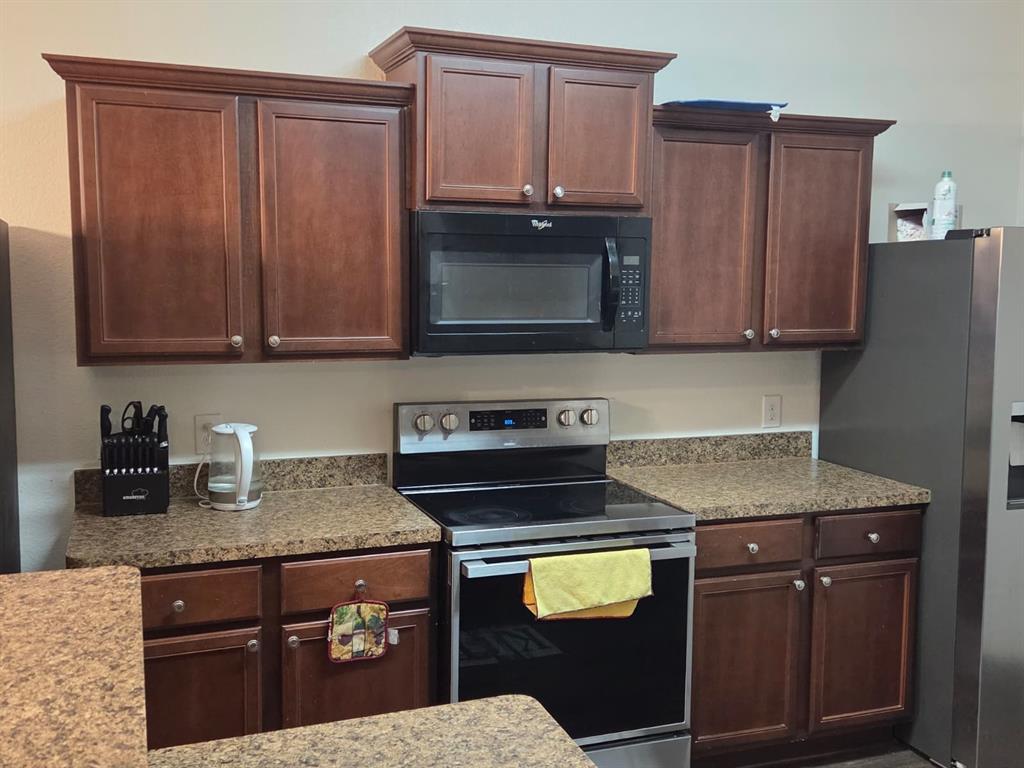 14249 Bridgeview Lane Dallas, TX 75253 - Photo 4 of 9 Kitchen with stainless steel appliances, light stone counters, and dark brown cabinets