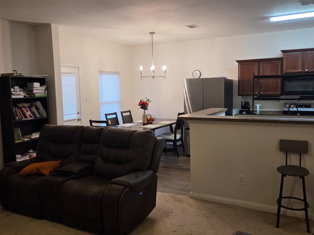 14249 Bridgeview Lane Dallas, TX 75253 - Photo 9 of 9 Living room featuring a chandelier, dark carpet, and dark wood-type flooring