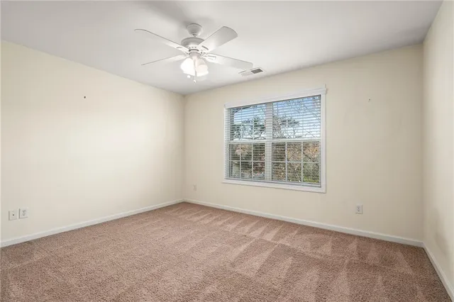 an empty room with a ceiling fan and a window