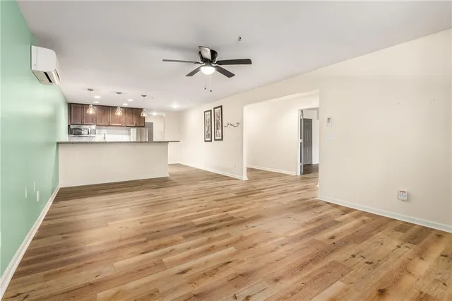 an empty room with wooden floor fan and windows
