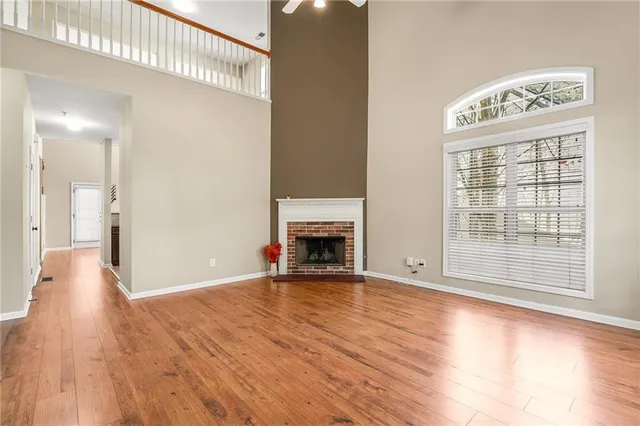 a view of an empty room with wooden floor and a fireplace